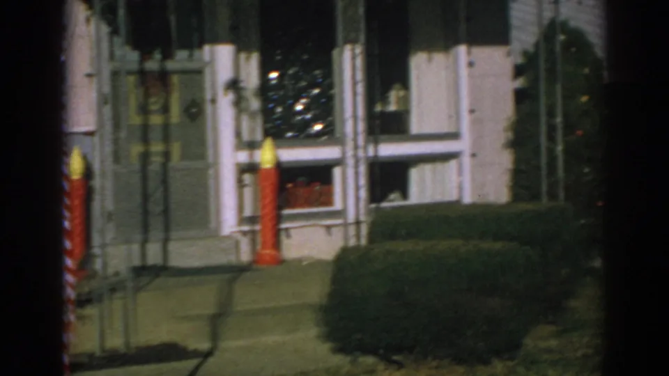 1962 Gary, Indiana exterior frame with a red candle decoration near the front door and a Christmas tree visible inside the window.
