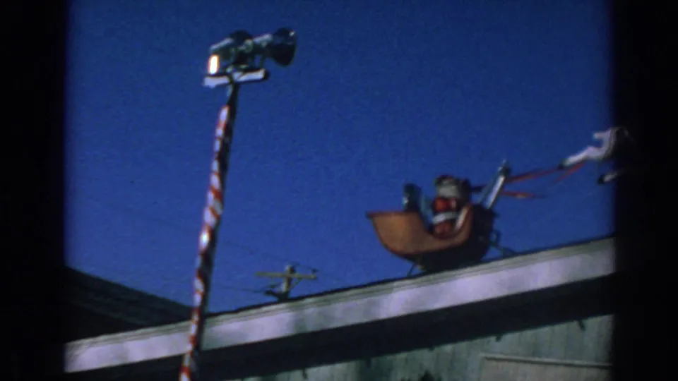 1962 Gary, Indiana frame with a rooftop Santa sleigh decoration and a striped pole against a blue sky.