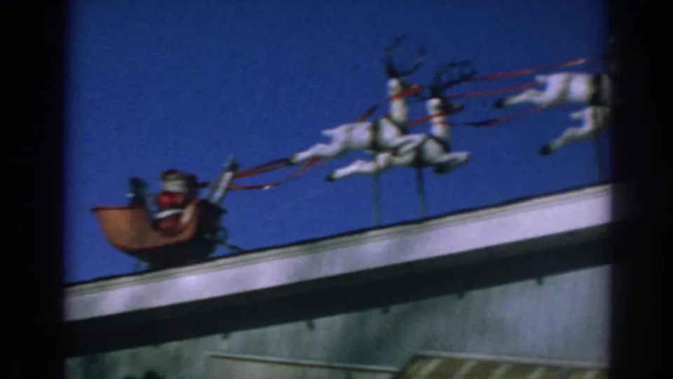1962 Gary, Indiana frame showing Santa in a sleigh with white reindeer decorations along a roofline.