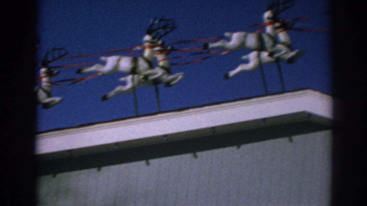 White rooftop reindeer figures with red reins against a deep blue sky.