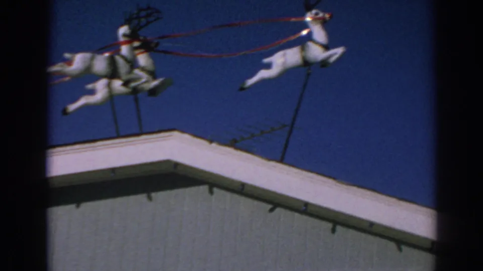 A closer 8mm view shows white reindeer decorations on poles above a rooftop in Gary, Indiana, with red reins visible.