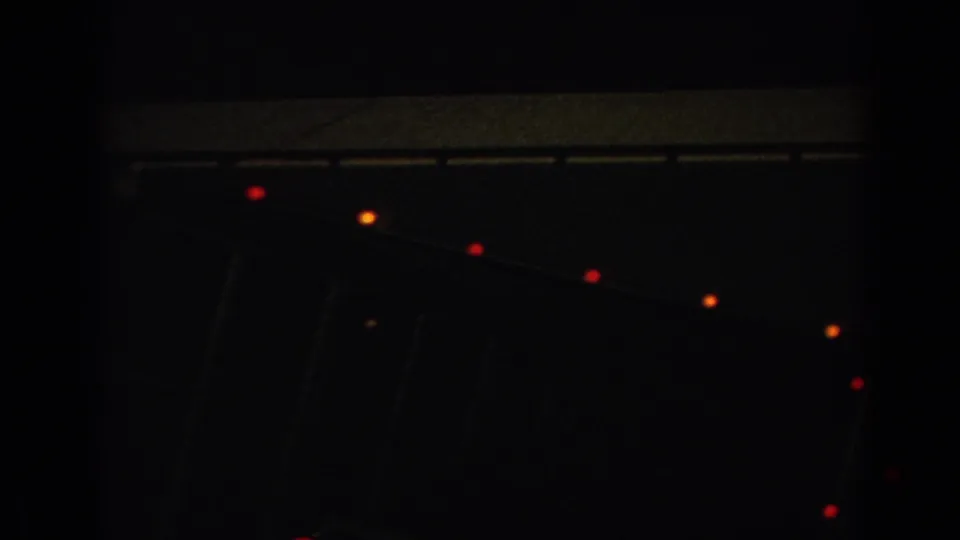 Nighttime 8mm frame shows a dark roofline with scattered red and orange lights, likely part of the same holiday display.