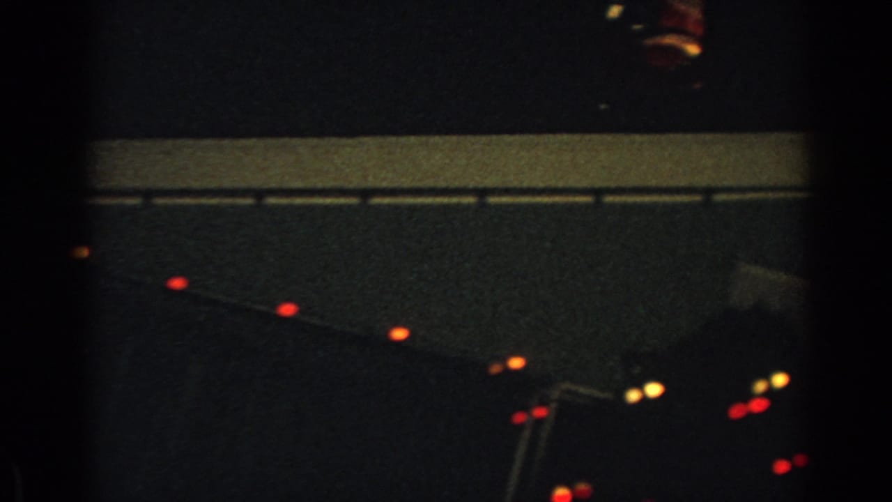 1962 Gary, Indiana 8mm frame showing red roofline lights and faint rooftop Christmas display elements at night.