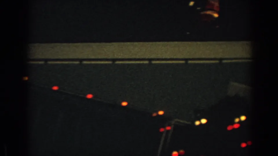 1962 Gary, Indiana 8mm frame showing red roofline lights and faint rooftop Christmas display elements at night.