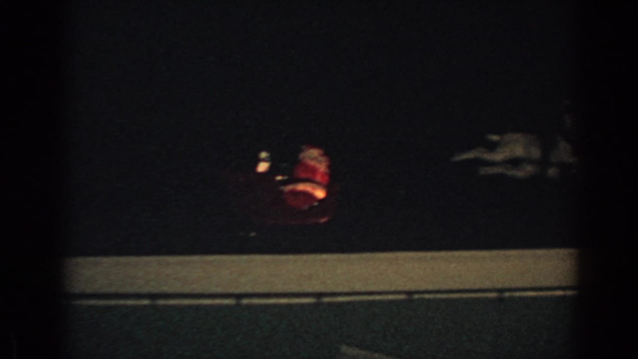 Dim Santa sleigh figure above a roofline in a nighttime holiday display.
