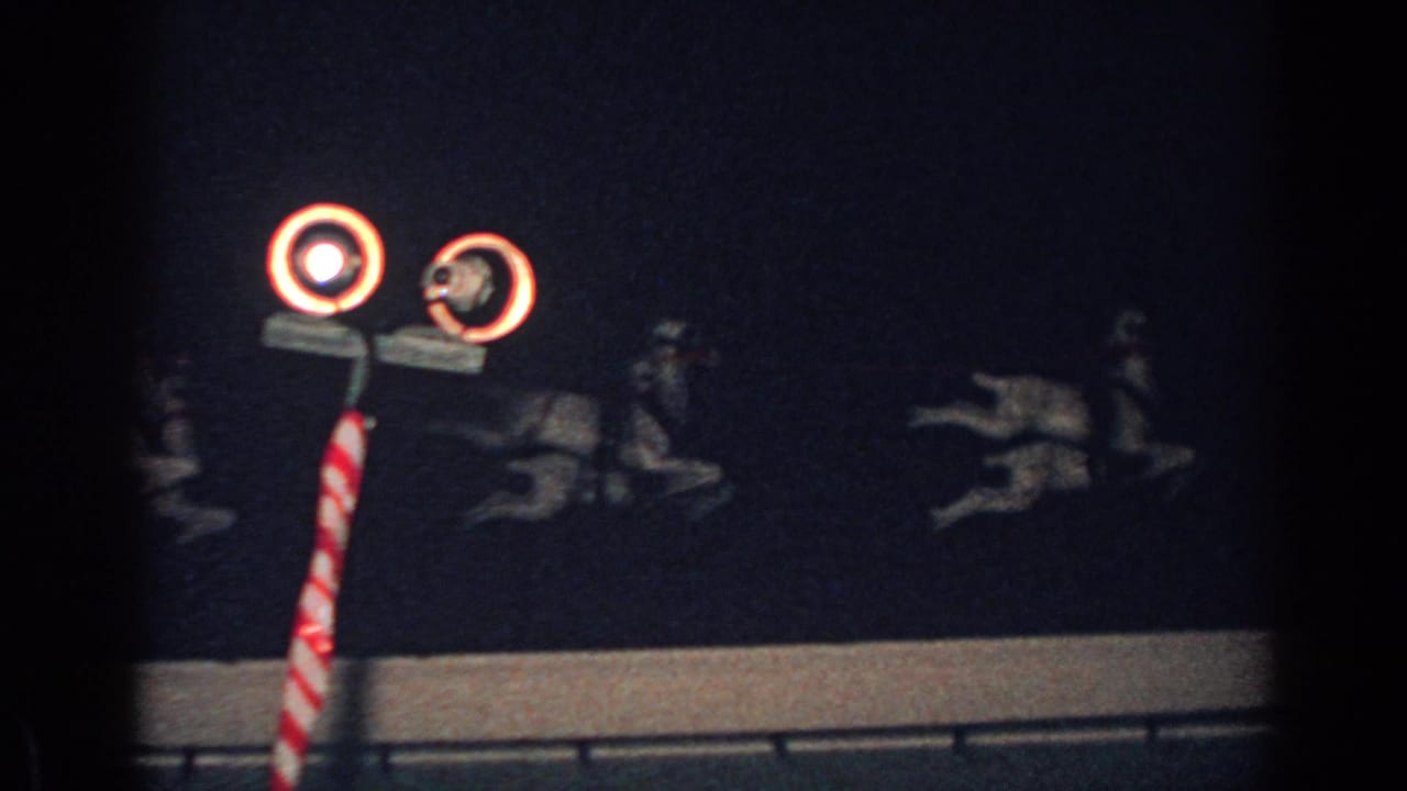 Rooftop Santa sleigh display with illuminated reindeer and a striped pole at night.