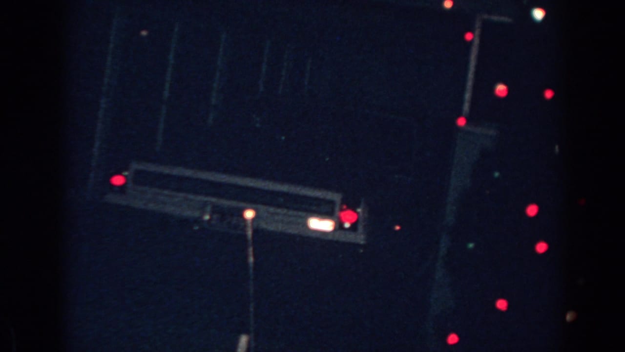 1962 Gary, Indiana home-movie frame showing red and white outdoor Christmas lights against a dark exterior.
