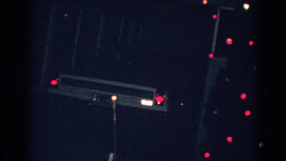 1962 Gary, Indiana home-movie frame showing red and white outdoor Christmas lights against a dark exterior.