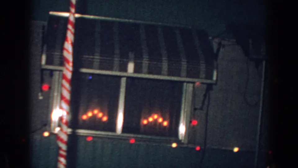 1962 Gary, Indiana 8mm frame showing a dim nighttime house exterior with a striped awning, red holiday lights, and a red-and-white candy-cane-style pole.
