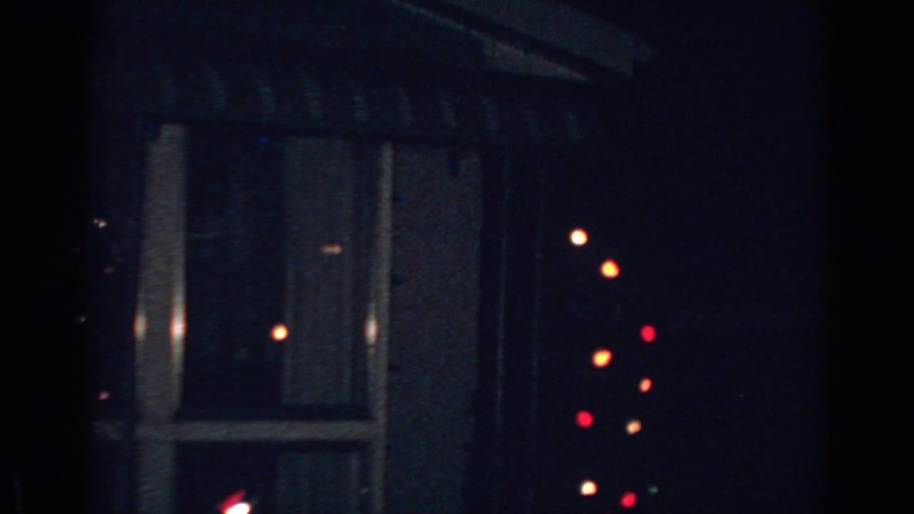Window and wall in darkness with out-of-focus colored bulbs nearby.