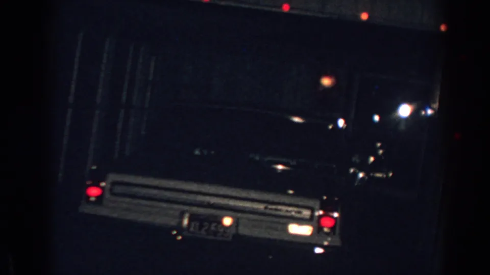 Final 1962 Gary, Indiana frame with a parked car, garage door, and scattered Christmas bulbs glowing in the dark.