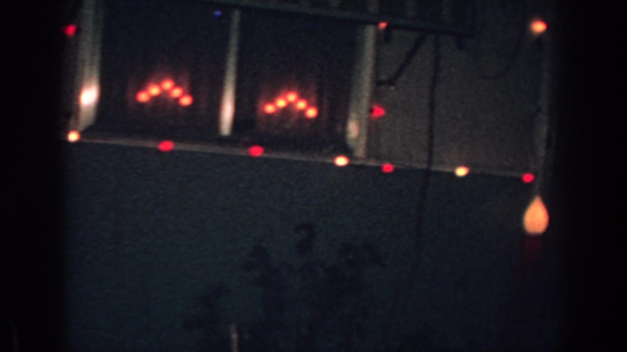 House exterior at night with red Christmas lights along the eaves.