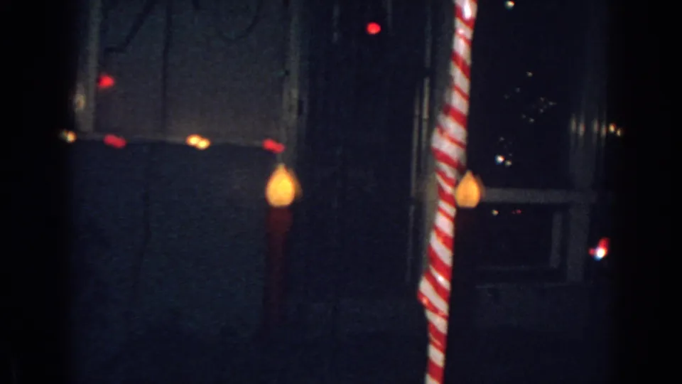 1962 Gary, Indiana frame showing a striped candy-cane holiday decoration beside a dim house exterior.