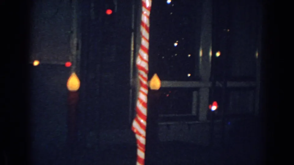 1962 Gary, Indiana nighttime home-movie frame with a candy-cane decoration near a dark residential window.