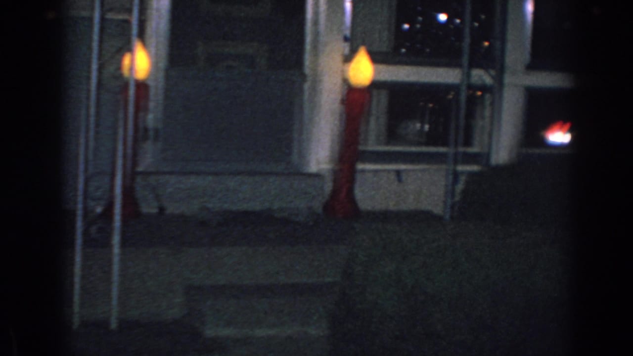 Night view of a house porch with two glowing candle-shaped Christmas lights.