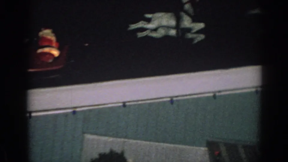 1962 Gary, Indiana 8mm frame showing white reindeer decorations along a dark roofline at night, with pale trim below.