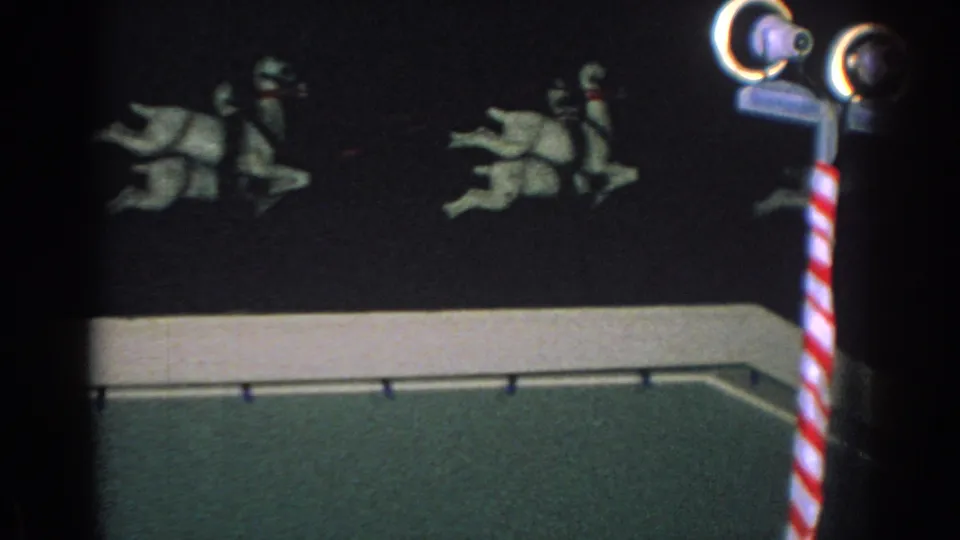 1962 home-movie frame of white reindeer figures on a roof, partly framed by a striped pole and lamp fixture at night.