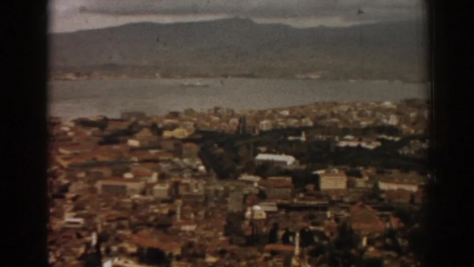 Wide 1962 home-movie view across Izmir and its bay, with distant hills and soft, grainy 8mm color.