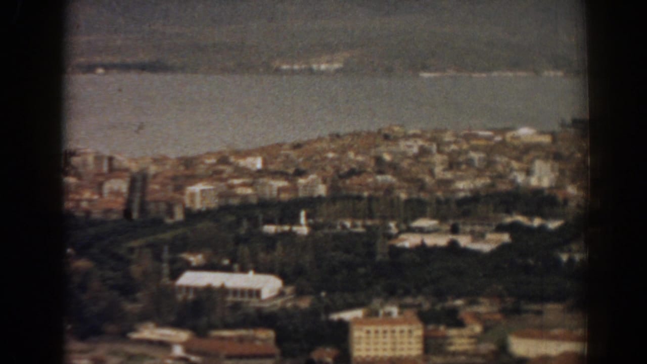 1962 8mm view over Izmir, Turkey, showing the bay, dense hillside housing, green trees and low urban buildings.