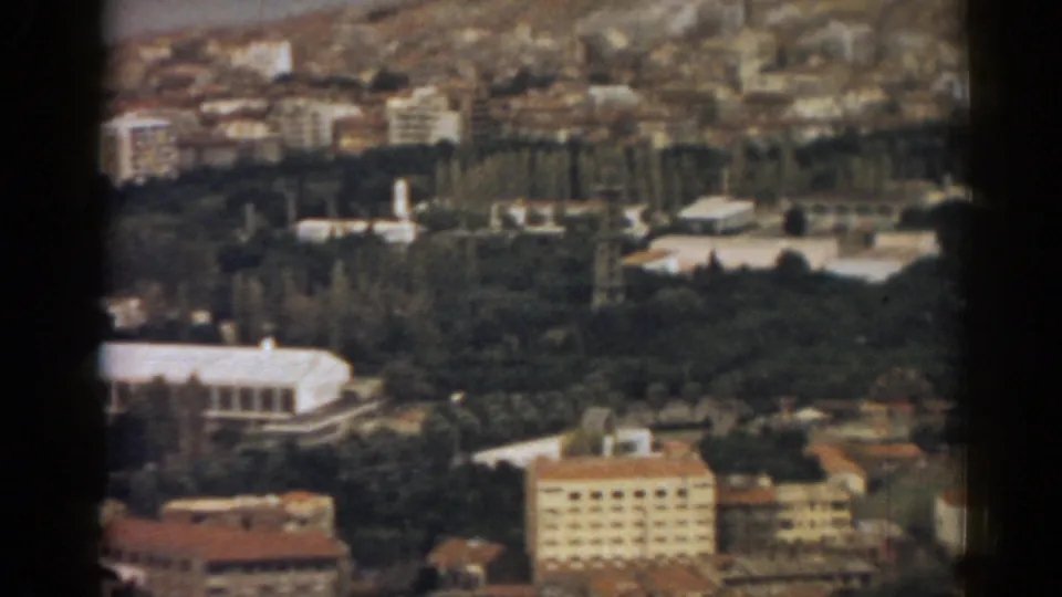 1962 Izmir aerial frame showing tree-lined grounds, pale low buildings, apartment blocks and red-brown rooftops.