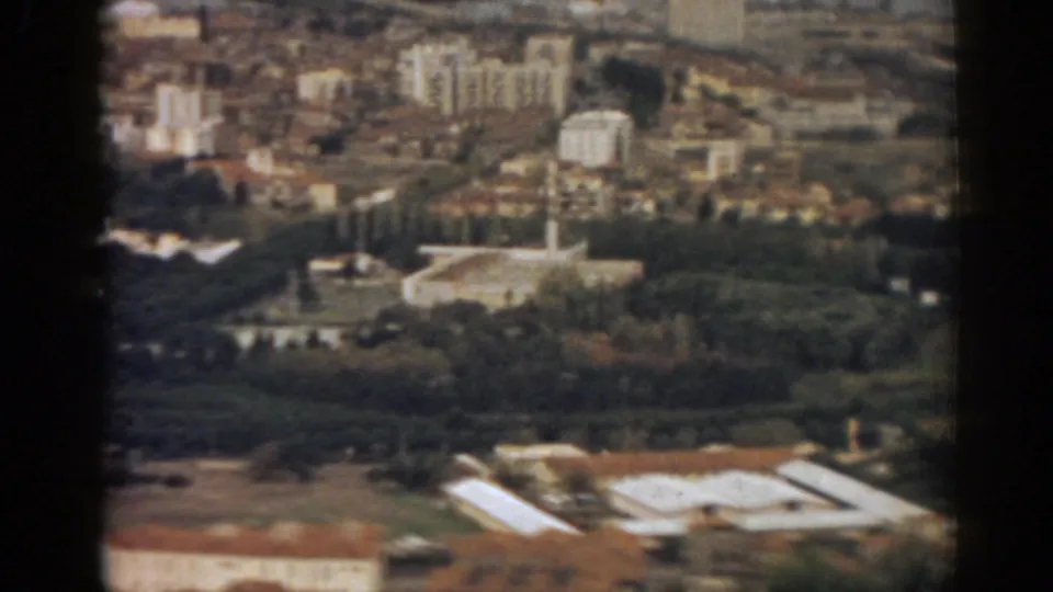 1962 Izmir view from above, with the mosque minaret more central against trees, rooftops and distant urban density.