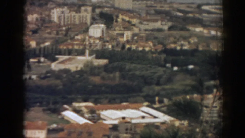 1962 Izmir aerial frame showing green urban grounds, mosque structures, rooftops and dense city blocks beyond.