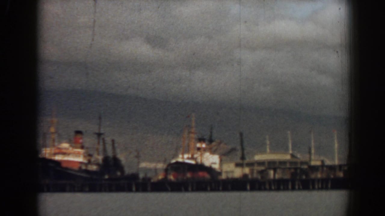 Several moored ships and pier structures viewed through dark film-frame edges.
