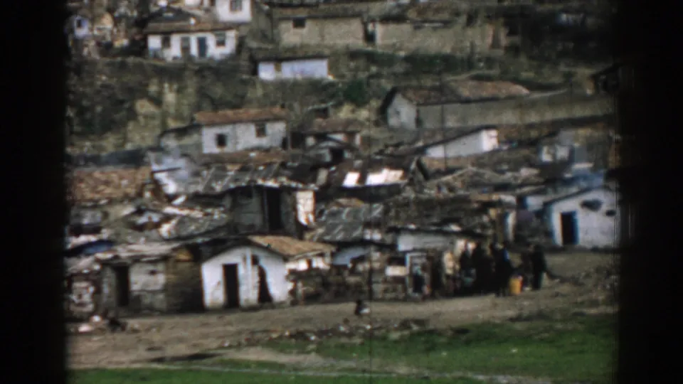 1962 Izmir hillside housing seen closer, with modest structures, rough paths, and distant people near the lower edge.