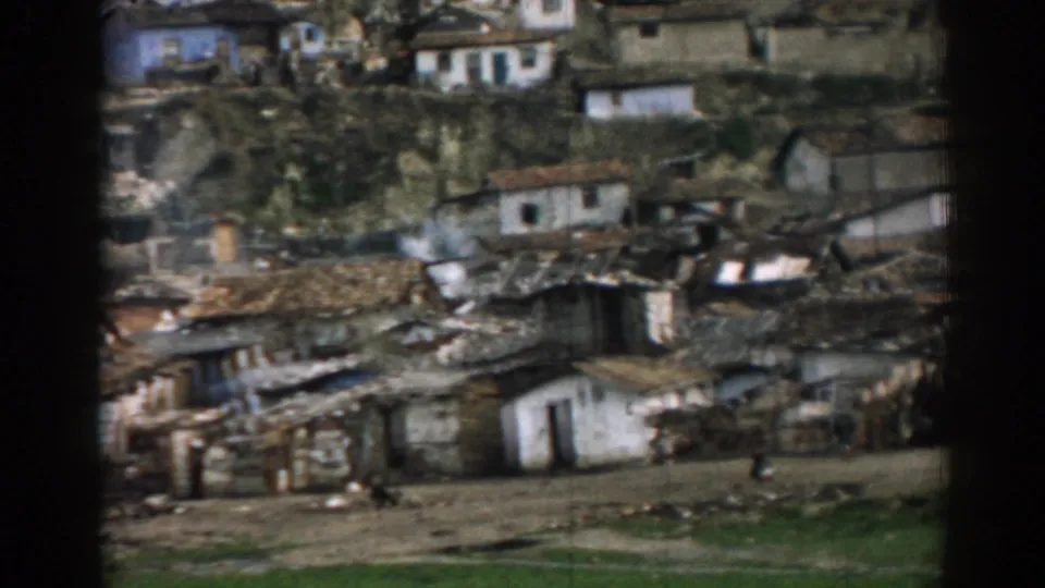1962 Izmir hillside settlement with white homes, uneven roofs, and a distant pedestrian along the lower path.