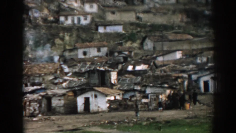 1962 Izmir hillside community with collapsed roofs, rubble, and residents gathered near fire-damaged homes.