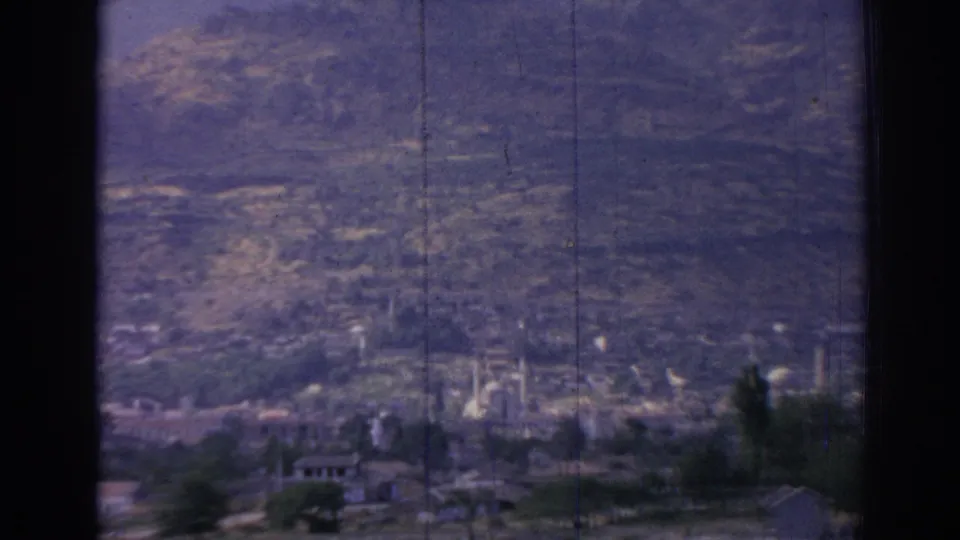 Closer 1962 Izmir frame emphasizing the mountain slope, with distant buildings and minarets along the lower edge.