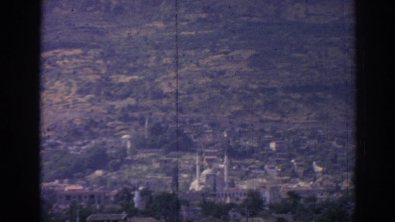 1962 8mm view over Izmir, Turkey, showing a distant city, mosque minarets, hills, and soft film grain from an elevated vantage point.