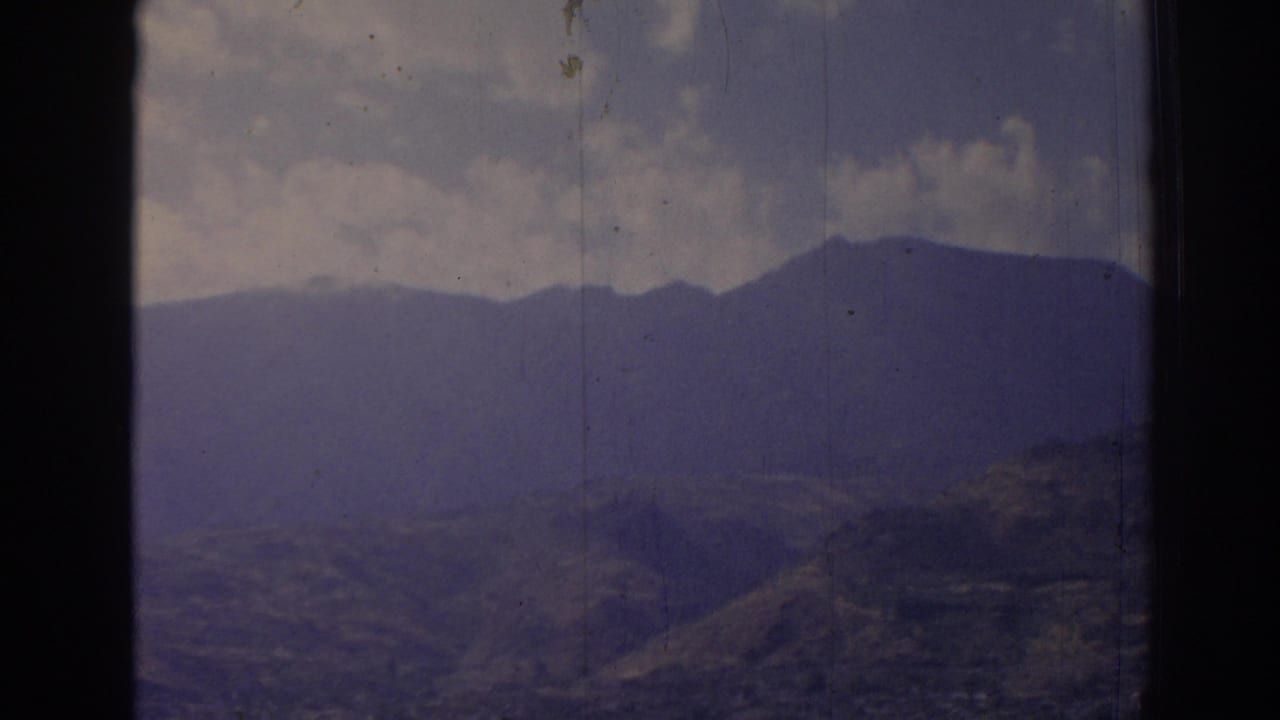 Mountain range and rolling hills behind a central dark window divider.