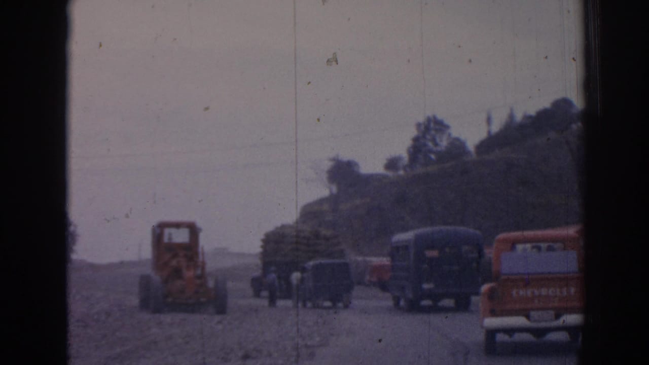 Orange tractor, buses, and an orange Chevrolet pickup are visible on a rural road.