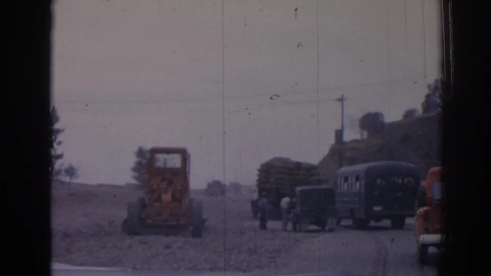 1962 Izmir frame showing roadwork equipment, buses, pedestrians, and a Chevrolet pickup along a rural dirt road.