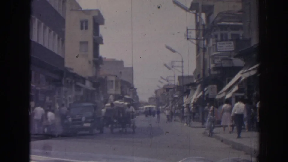 Izmir, Turkey street scene from 1962 with sidewalk pedestrians, cars, shop awnings, balconies, and visible business signs.