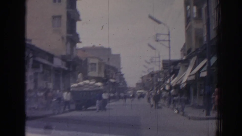 Street traffic in Izmir, Turkey, with a sack-loaded truck ahead and blurred pedestrians near shopfronts.