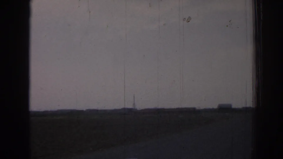 A later 1962 Izmir frame shifts to open roadside fields, a low horizon, distant structures, and visible 8mm gate edges.