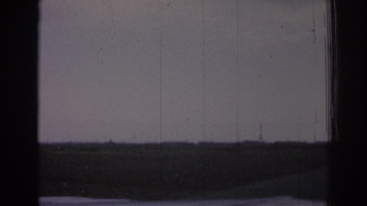 Distant power towers on a flat horizon, partially framed by dark vertical borders.