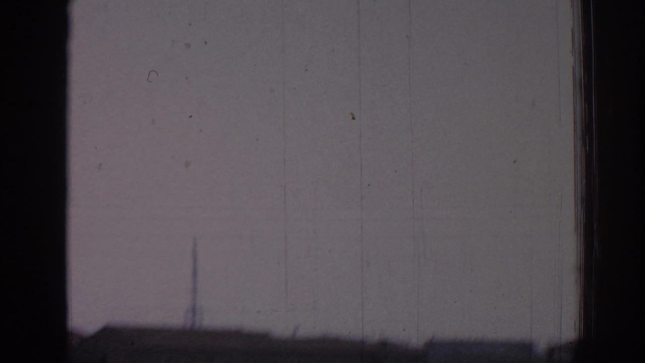 Window frame divides a soft exterior view with faint buildings or horizon in the distance.