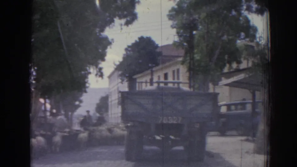 A numbered military-style truck is prominent on an Izmir street in 1962, with sheep and pedestrians partly visible around it.