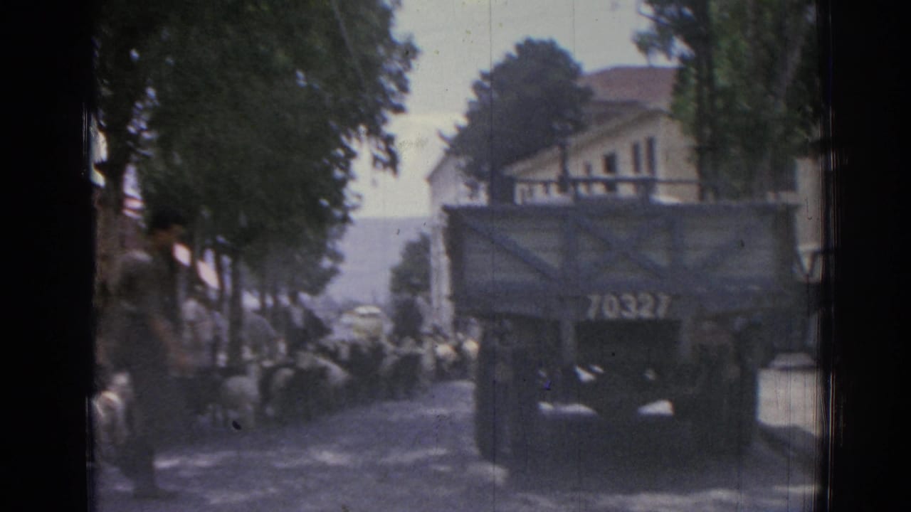 A truck marked 70327 stands near sheep and pedestrians on a shaded street.