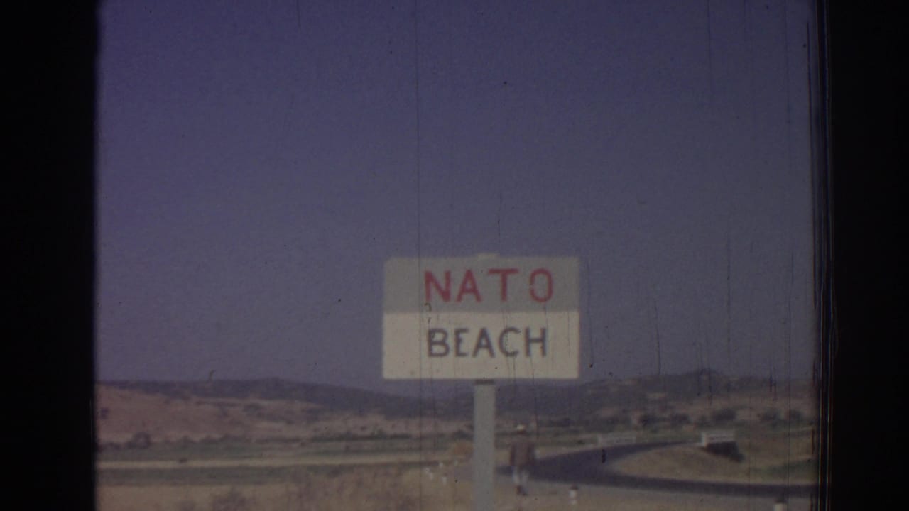 NATO Beach sign beside a road with open hills beyond.