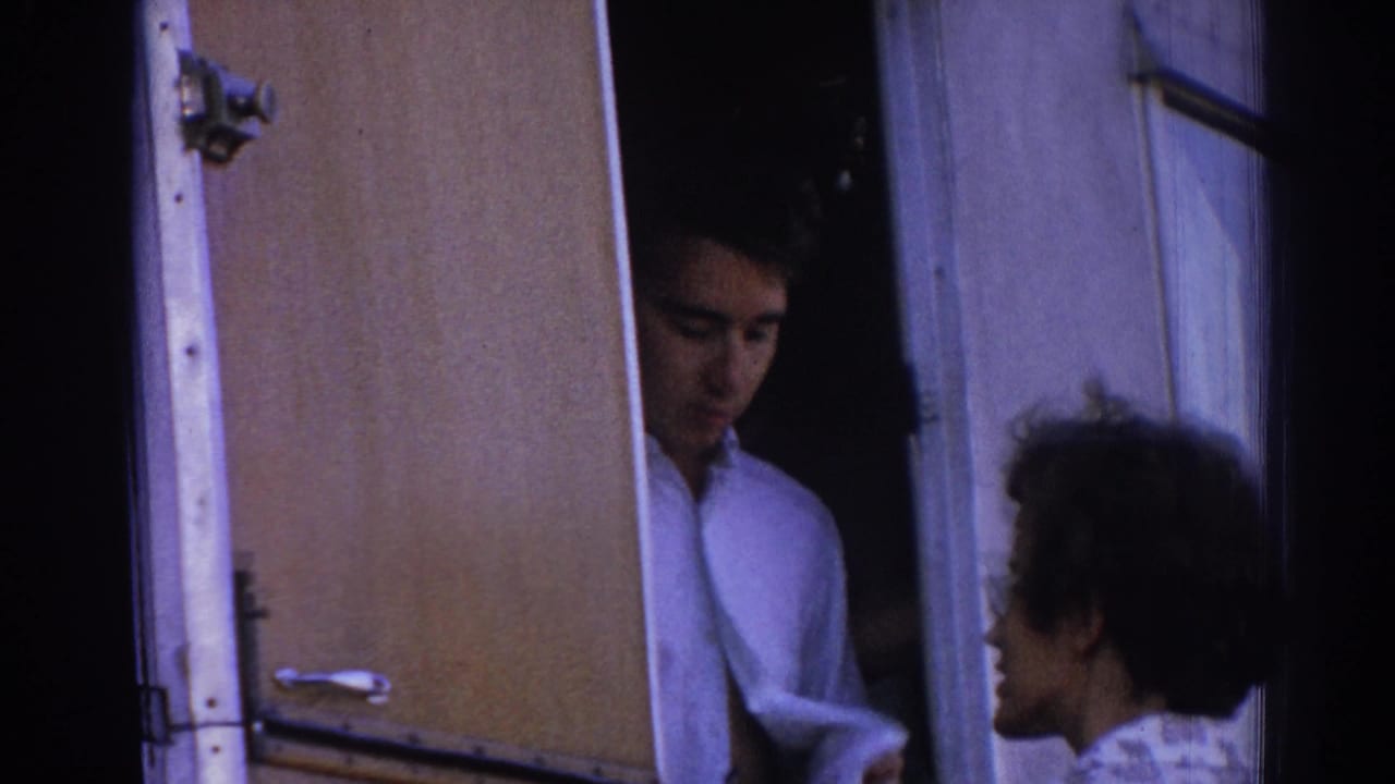 Man standing in an open camper doorway while a woman faces him outside.
