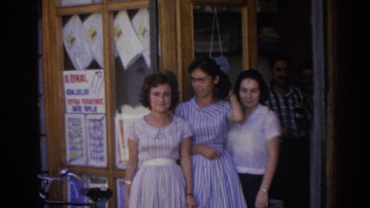 Three women stand smiling outside a shop doorway with signs and clothing in the window.