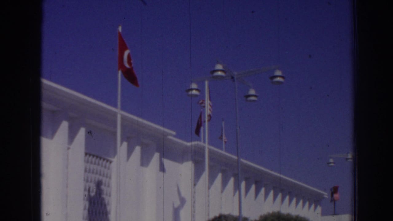 Turkish flag and white modern building under a blue sky.