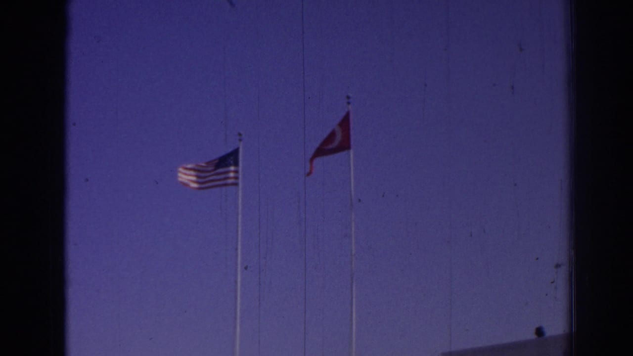 U.S. and Turkish flags on tall poles above a white venue building.