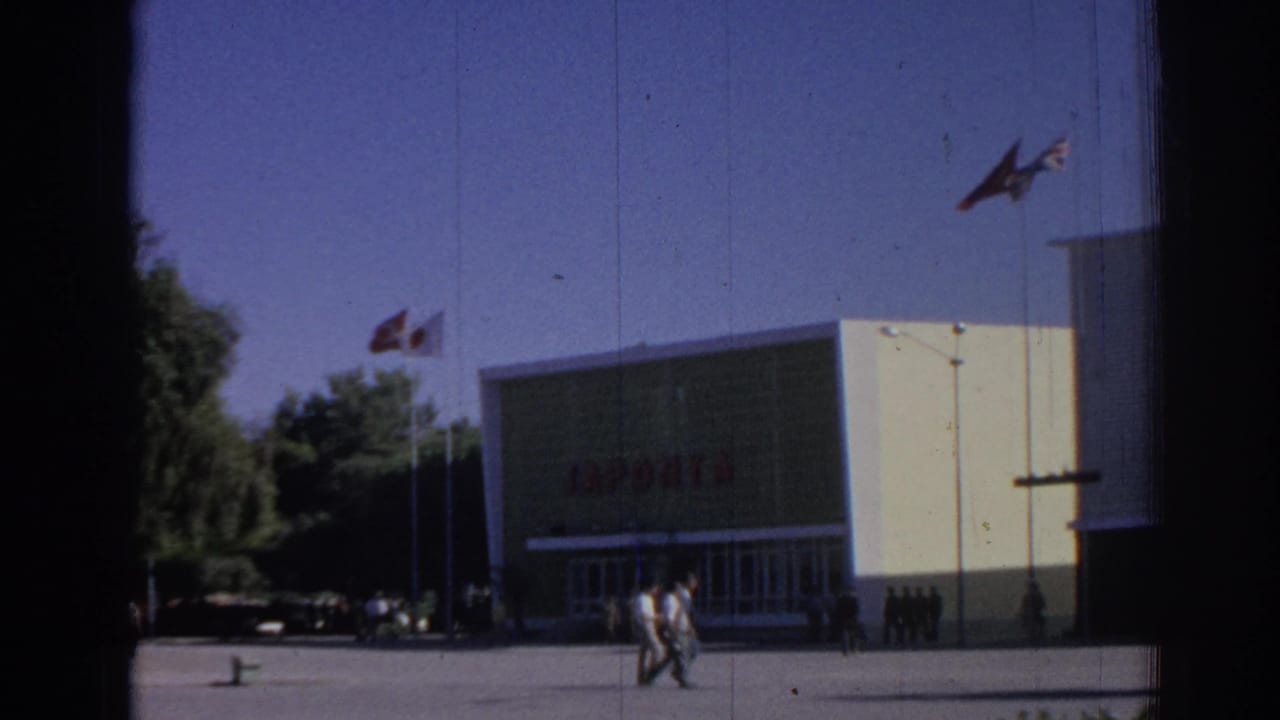 Building entrance with red JAPONTA lettering, flags, pedestrians, and open plaza.