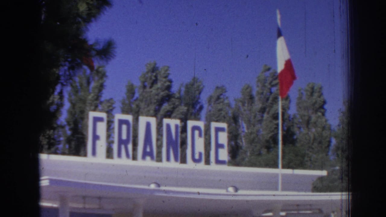 FRANCE sign on a pavilion roof with a French flag above trees and blue sky.