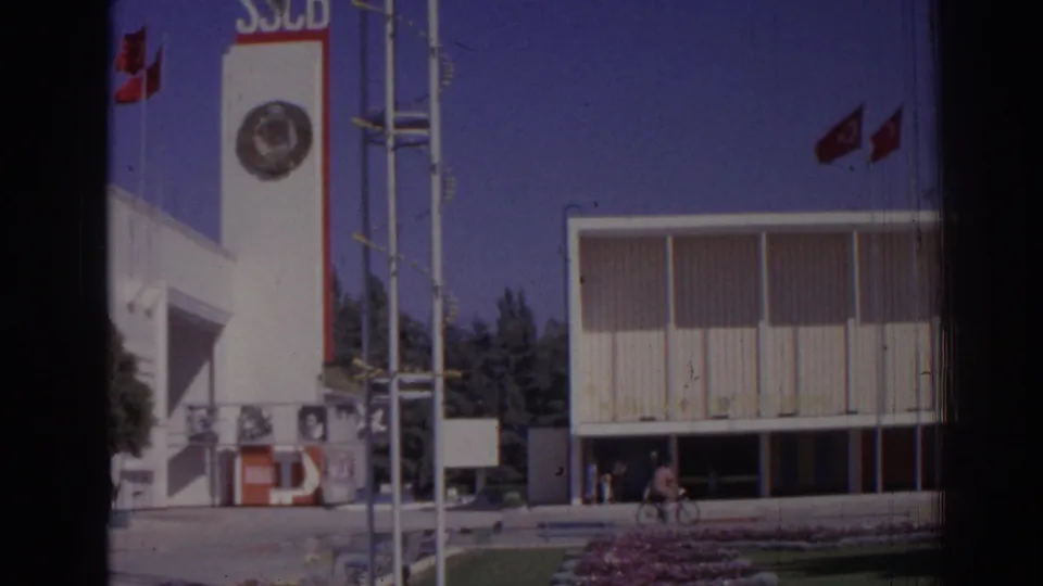 1962 Izmir wider exterior showing the SSCB tower, red flags, antenna structure, modern facade, landscaping, and distant people.